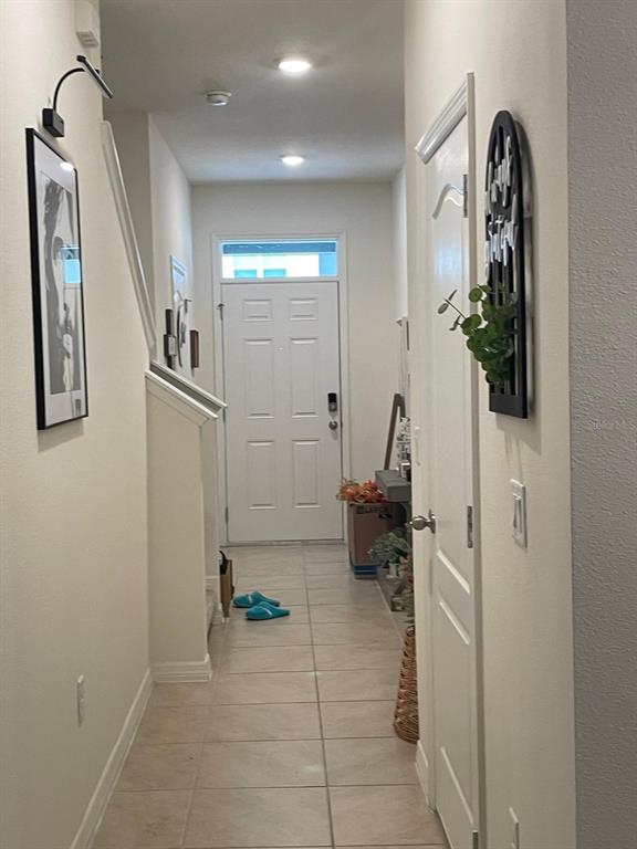 A tiled hallway leads to a white front door with a staircase on the left — 1428 PLANK PLACE, DAVENPORT, FL