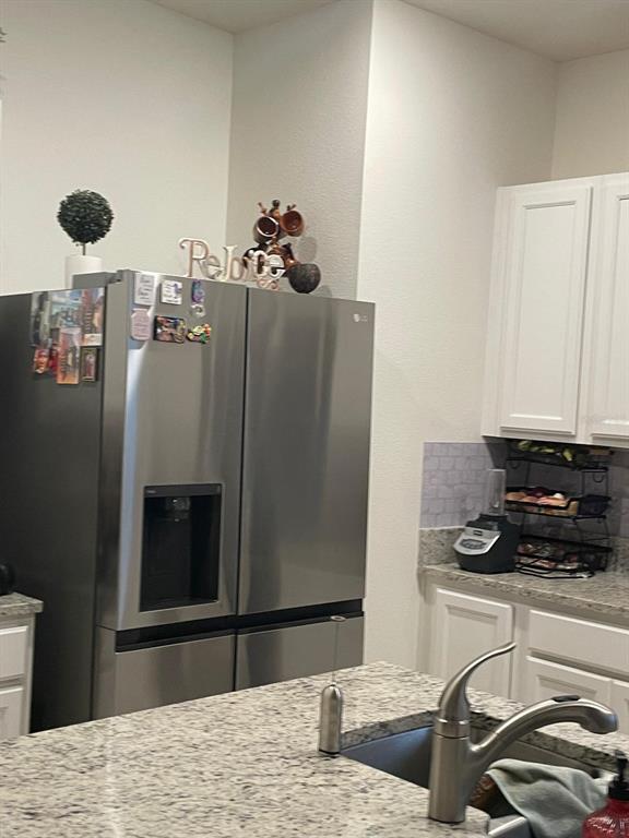 A stainless steel refrigerator stands in a kitchen with white cabinets and granite countertops — 1428 PLANK PLACE, DAVENPORT, FL