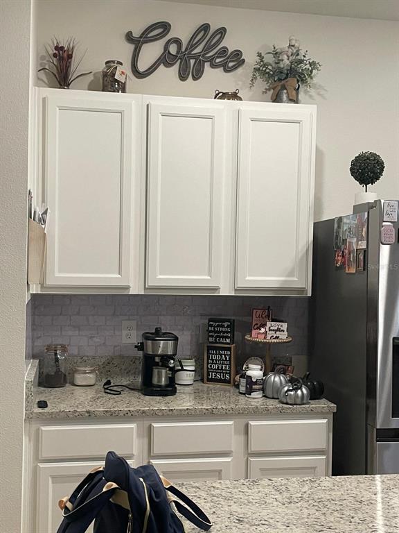 A kitchen coffee station features white cabinets, granite countertops, and a faux brick backsplash — 1428 PLANK PLACE, DAVENPORT, FL