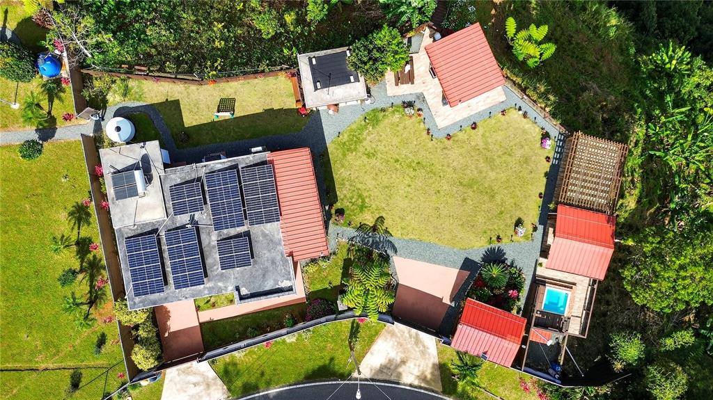 An aerial view shows a house with solar panels, a grassy yard, and several outbuildings — PARCEL A ALTURITAS COLLORES, OROCOVIS, PR