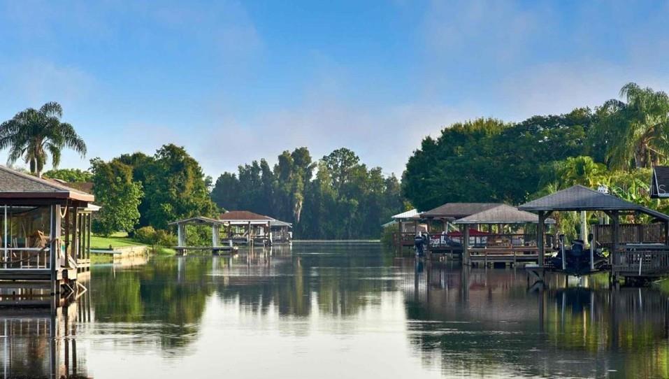 A canal view featuring multiple covered boat docks along the water with lush green trees — 6 EL DORADO DRIVE, INDIAN LAKE ESTATES, FL