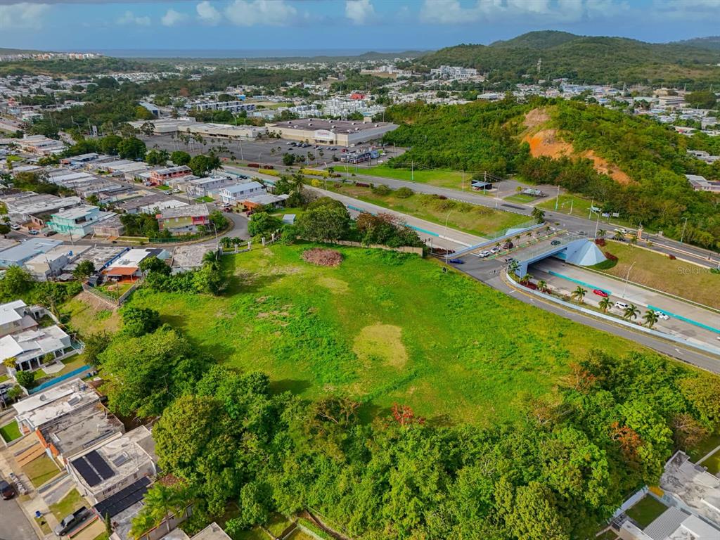 An aerial view shows a large, grassy vacant lot situated next to a highway overpass — Calle F URB MELENDEZ, FAJARDO, PR