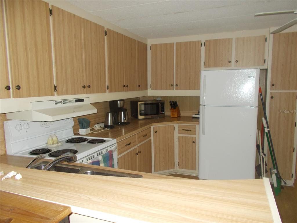 A kitchen features light wood-grain cabinets, white appliances, and a laminate countertop — 5231 PALENA BOULEVARD, NORTH PORT, FL