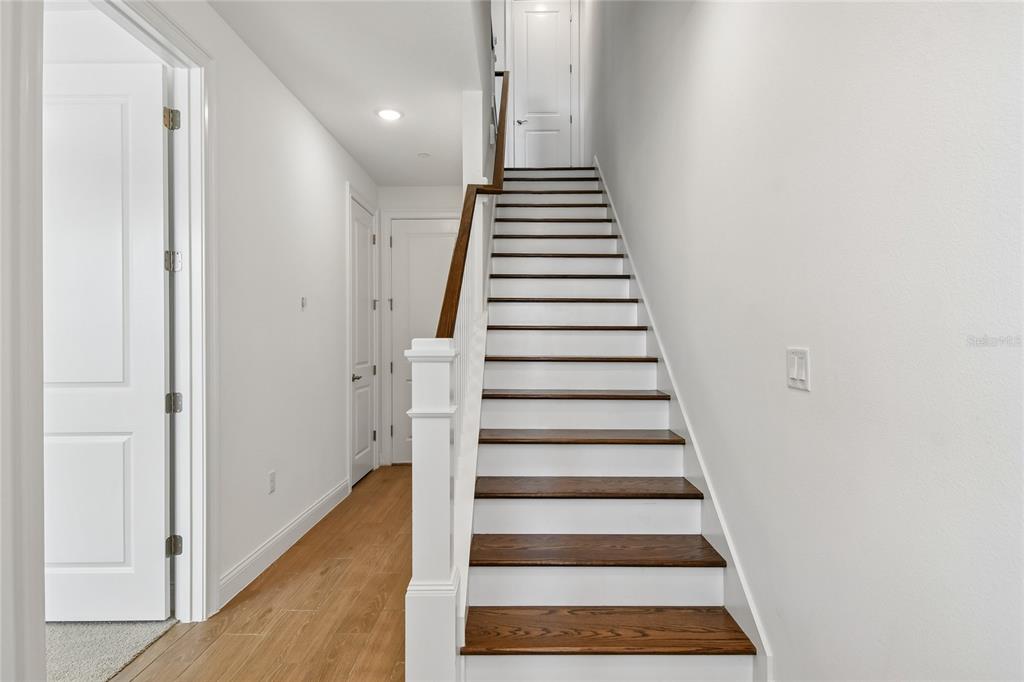 A staircase with dark wood treads and white risers leads to an upper landing — 210 PAQUALA, OVIEDO, FL