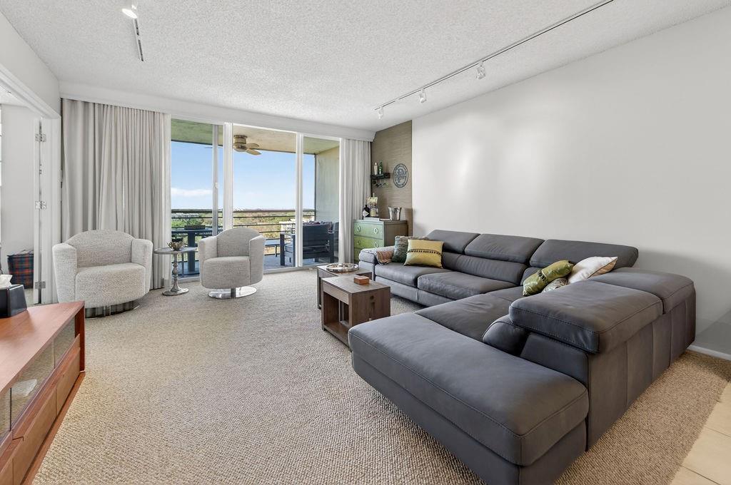 A living room features a large gray sectional sofa, two armchairs, and a balcony view — 575 Oaks Lane # 1002, Pompano Beach FL 33069, POMPANO BEACH, FL