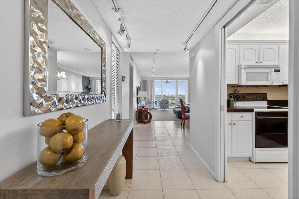 A hallway with a console table and mirror leads to an open living area and kitchen — 575 Oaks Lane # 1002, Pompano Beach FL 33069, POMPANO BEACH, FL