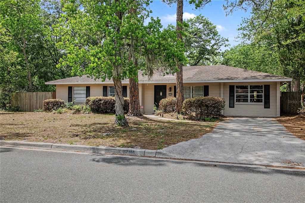 A single-story house with a beige exterior, dark shutters, and a concrete driveway — 6206 NW 27TH TERRACE, GAINESVILLE, FL