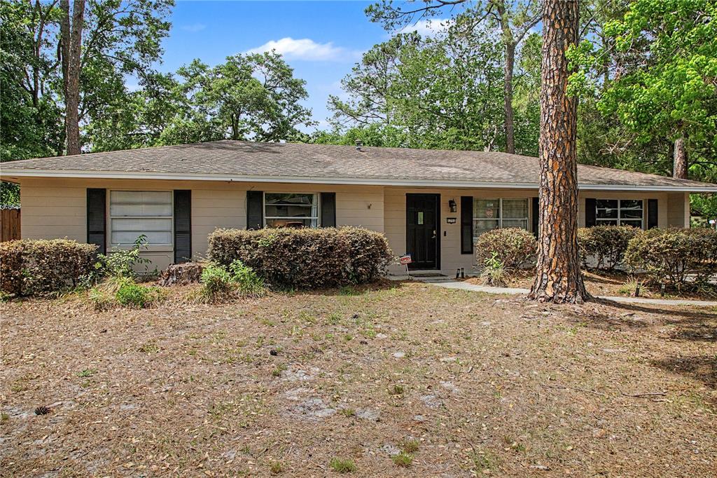 A single-story ranch-style house with beige siding, black shutters, and a dark front door — 6206 NW 27TH TERRACE, GAINESVILLE, FL