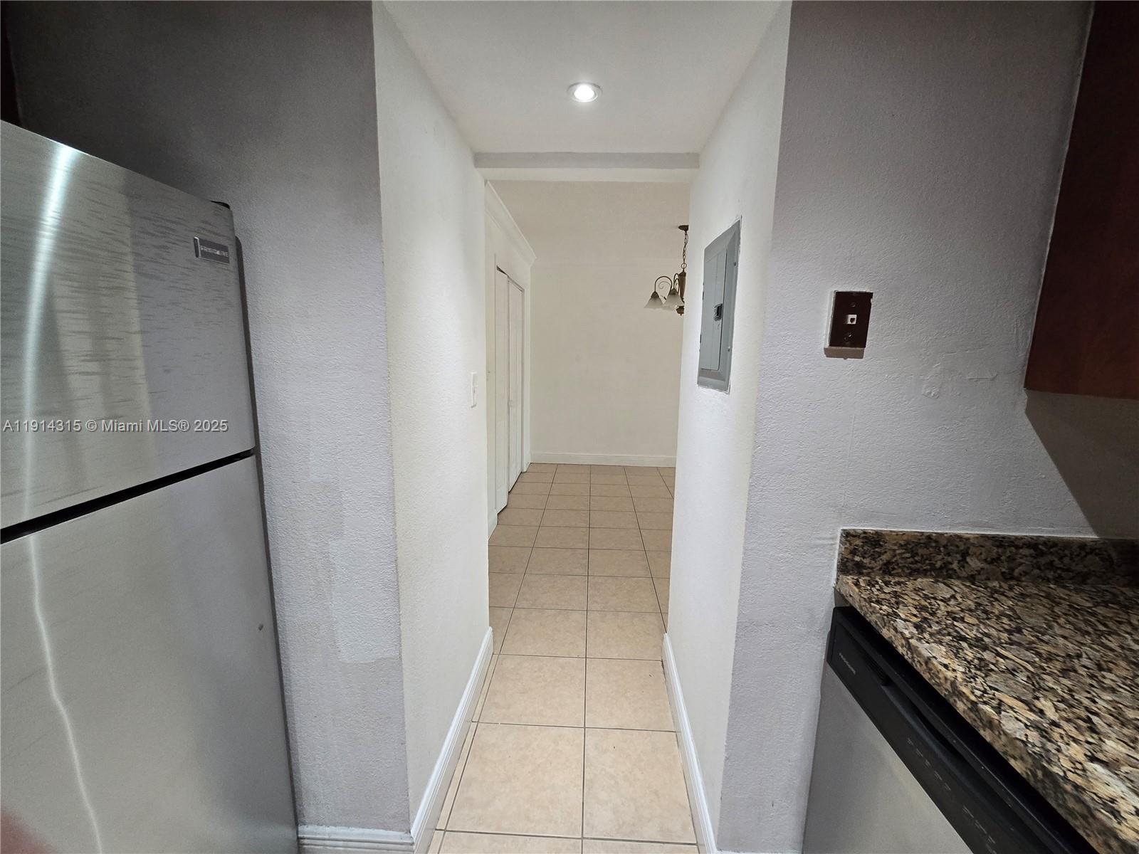 A narrow tiled hallway connects a kitchen with stainless steel appliances to an adjacent room — 6940 Miami Gardens Dr # 319, Hialeah FL 33015, HIALEAH, FL