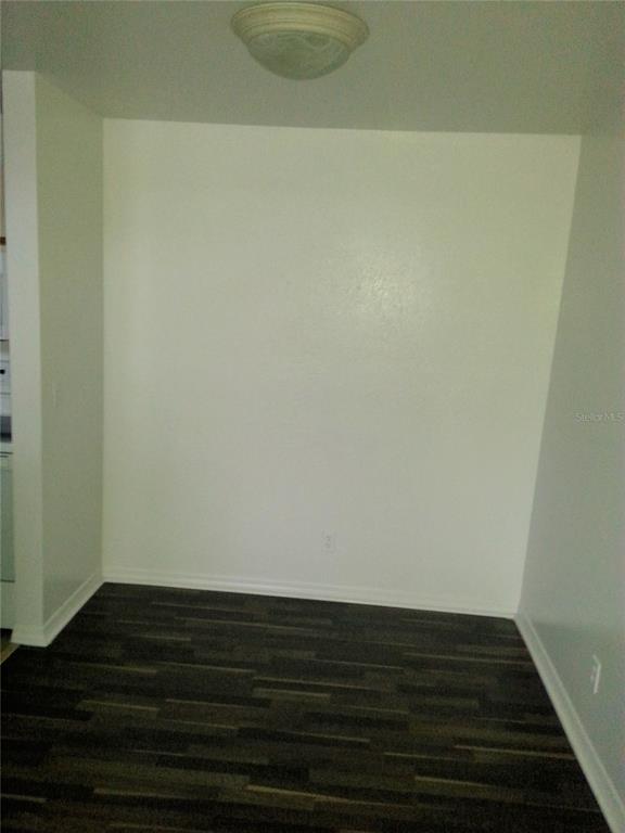 An empty room features dark wood-look flooring, white walls, and a flush-mount ceiling light — 6028 WESTGATE DRIVE UNIT 202, ORLANDO, FL