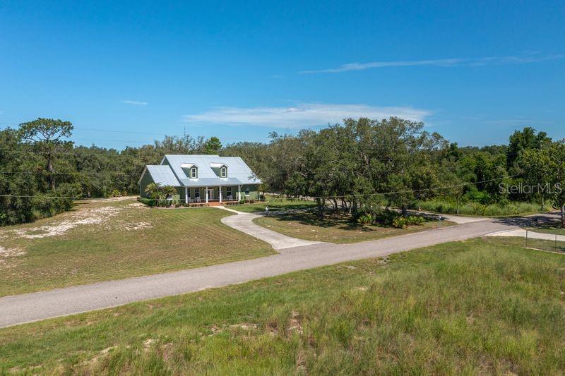An aerial view shows a green house with a metal roof and driveway on a lot — 35 STEMBRIDGE ROAD, LAKE WALES, FL