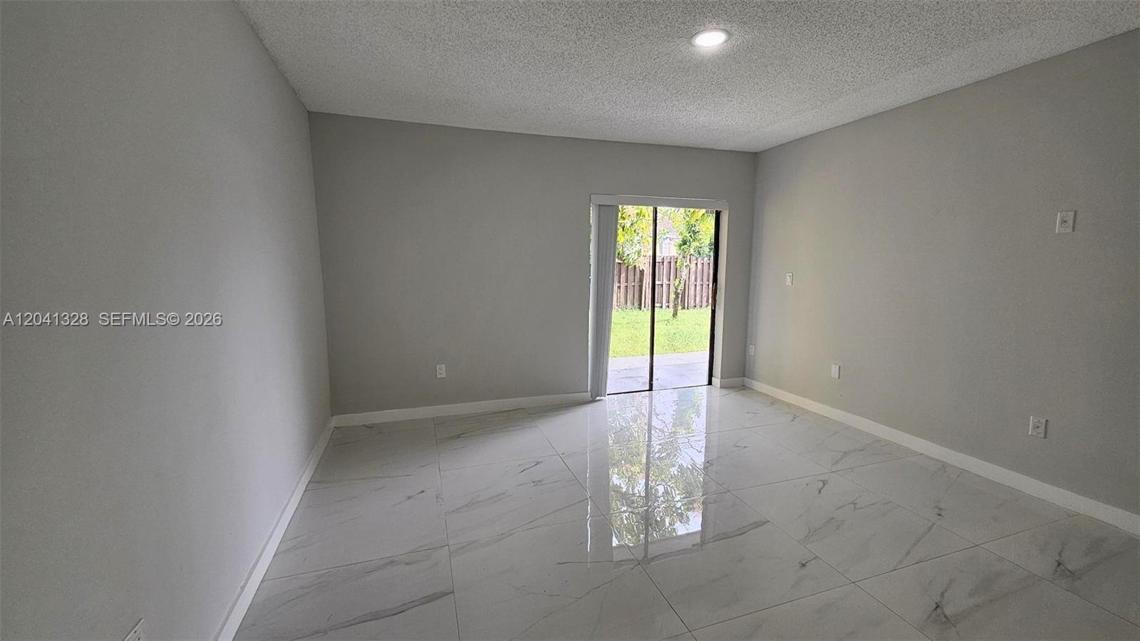 A room with light gray walls, white marble-patterned tile flooring, and a sliding glass door — 14470 SW 96th Ter, Miami FL 33186, MIAMI, FL