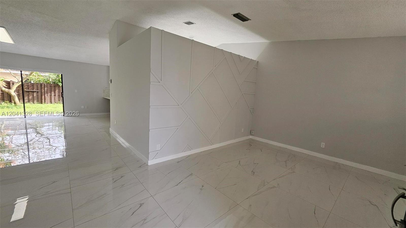 A room with white marble-look tile floors and a geometric accent wall — 14470 SW 96th Ter, Miami FL 33186, MIAMI, FL