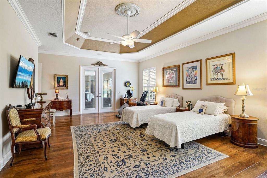 A bedroom with two twin beds, hardwood floors, a tray ceiling, and a large rug — 1404 BRIER CREEK CIRCLE, THE VILLAGES, FL