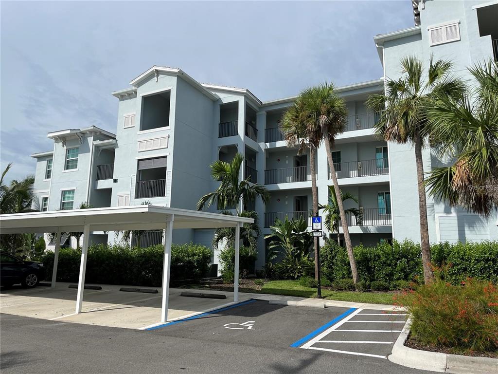A multi-story apartment building with a covered parking structure and a handicap-accessible parking space — 14091 HERITAGE LANDING BOULEVARD UNIT 124, PUNTA GORDA, FL