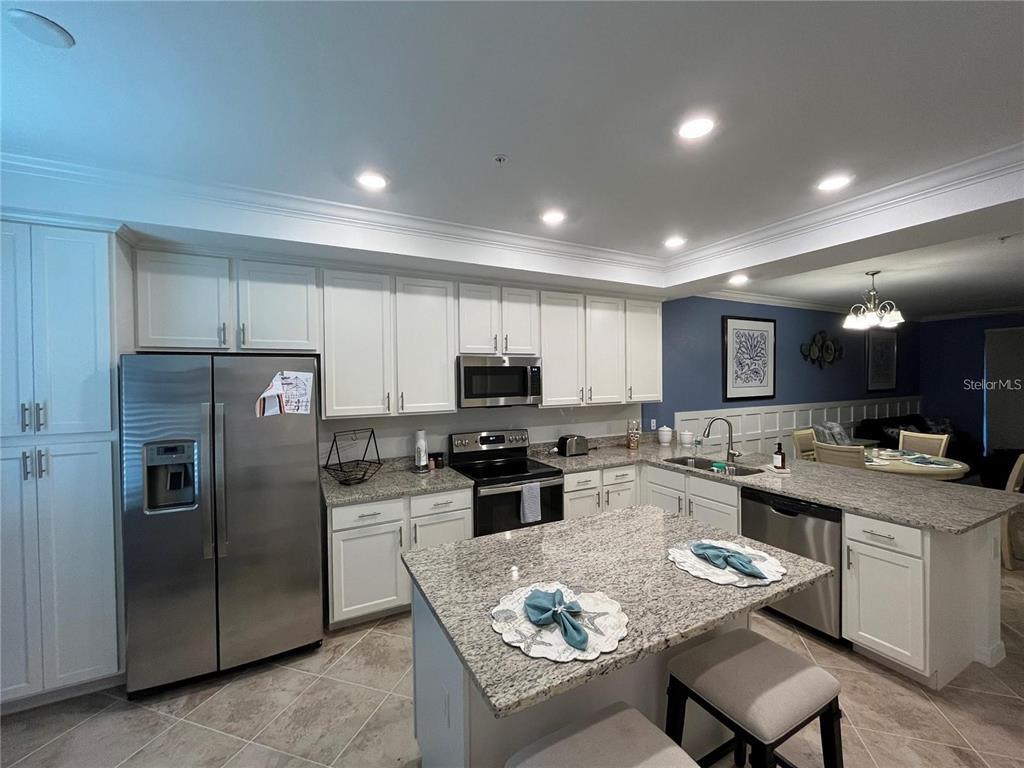 A kitchen features white cabinets, granite countertops, stainless steel appliances, and a central island — 14091 HERITAGE LANDING BOULEVARD UNIT 124, PUNTA GORDA, FL
