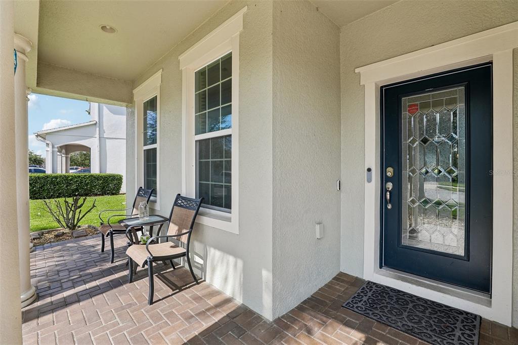 A covered front porch features brick pavers, two chairs, and a dark door with glass — 12255 STONE BARK TRAIL, ORLANDO, FL