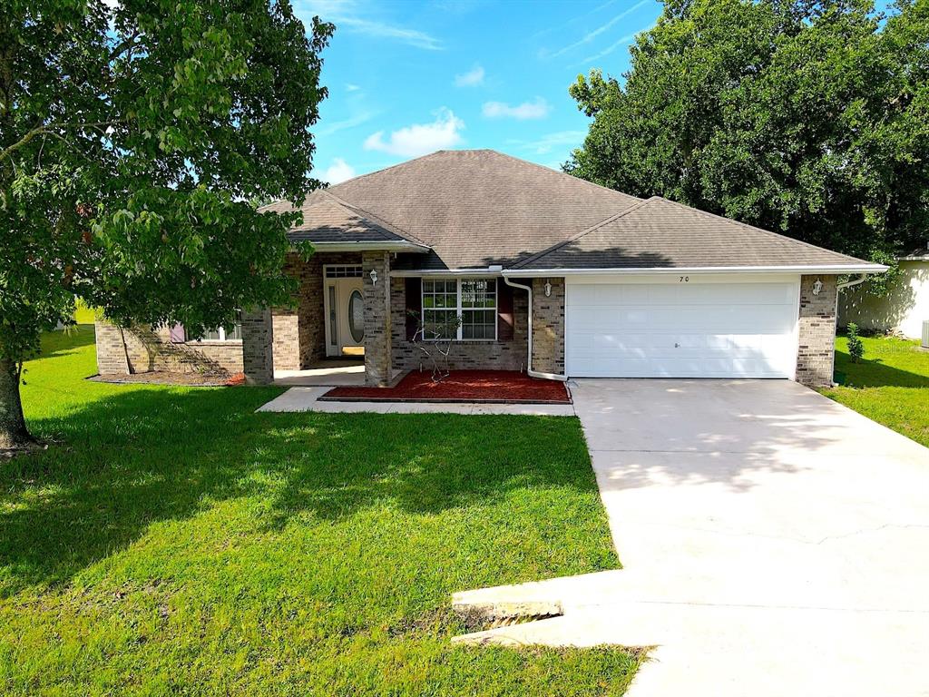 A single-story brick house with a two-car garage, a front porch, and a grassy lawn — 70 PHEASANT DRIVE, PALM COAST, FL