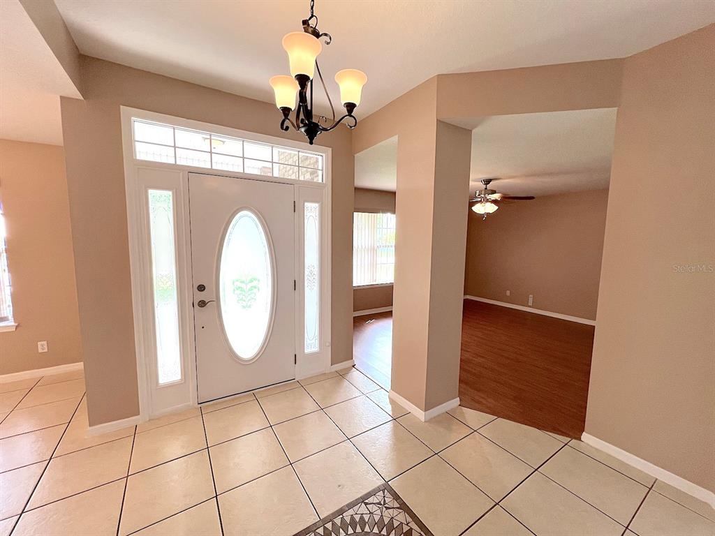 An entryway with tiled floors, a white front door, and a hanging light fixture — 70 PHEASANT DRIVE, PALM COAST, FL