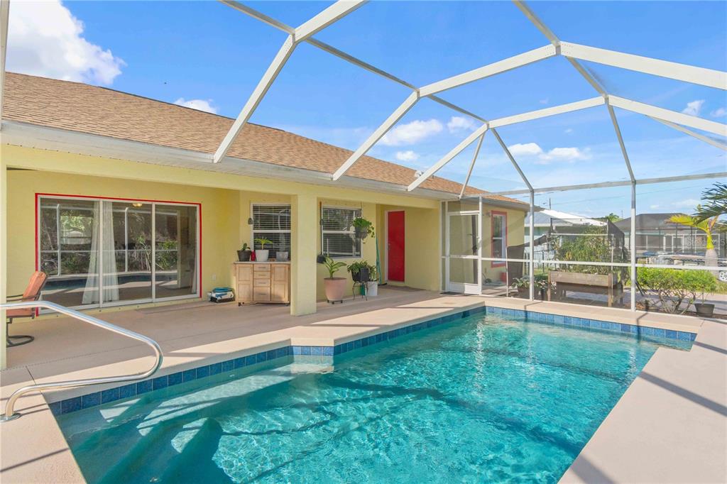A screened-in patio features a swimming pool with blue tile trim and a concrete deck — 18204 ACKERMAN AVENUE, PORT CHARLOTTE, FL
