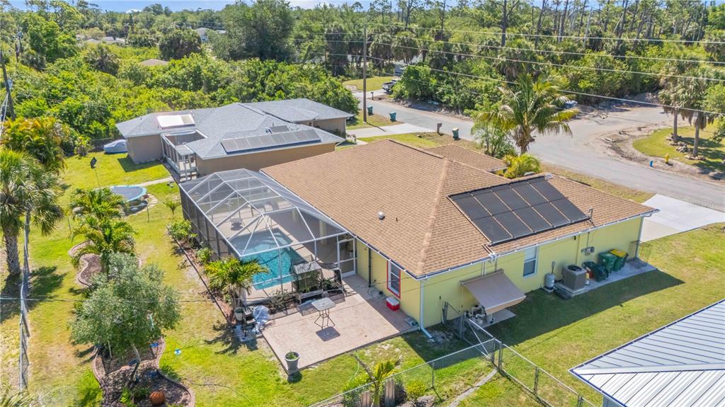 An aerial view shows a yellow house with a pool enclosure and solar panels — 18204 ACKERMAN AVENUE, PORT CHARLOTTE, FL