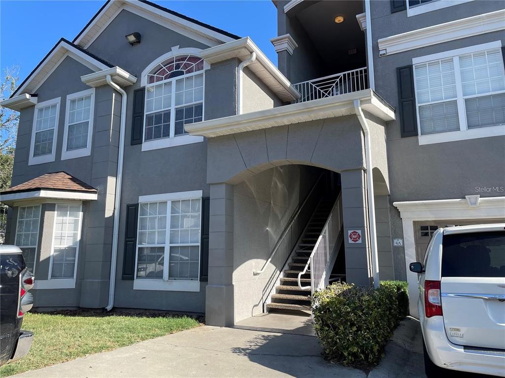 A two-story gray stucco building features a covered staircase, arched entryway, and attached garage — 3325 S KIRKMAN ROAD UNIT 420, ORLANDO, FL