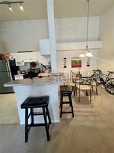 A kitchen with a breakfast bar, two stools, and an adjacent dining area with bicycles — 3325 S KIRKMAN ROAD UNIT 420, ORLANDO, FL