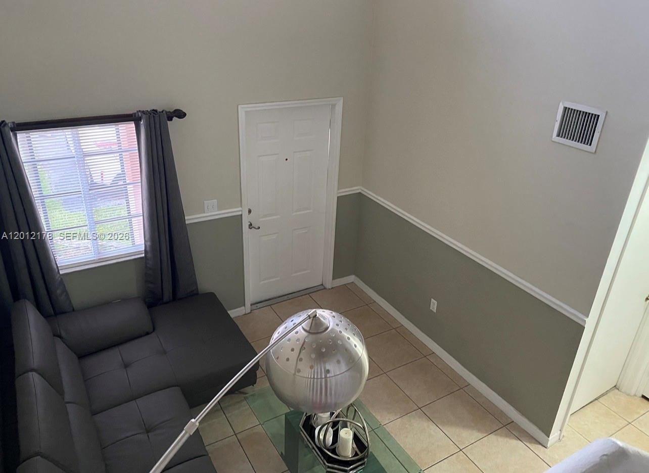A high-angle view of a living room with tile floors, a gray sofa, and a door — 6995 NW 173rd Dr # 2105, Hialeah FL 33015, HIALEAH, FL