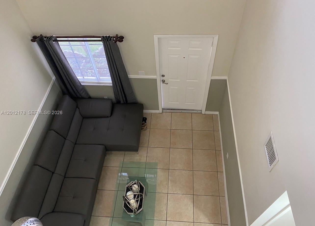 An elevated view of a living room with tile flooring, a gray sectional sofa, and a door — 6995 NW 173rd Dr # 2105, Hialeah FL 33015, HIALEAH, FL