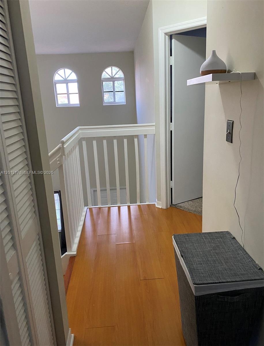 A hallway with wood flooring, a white railing, and an arched window overlooks a lower level — 6995 NW 173rd Dr # 2105, Hialeah FL 33015, HIALEAH, FL