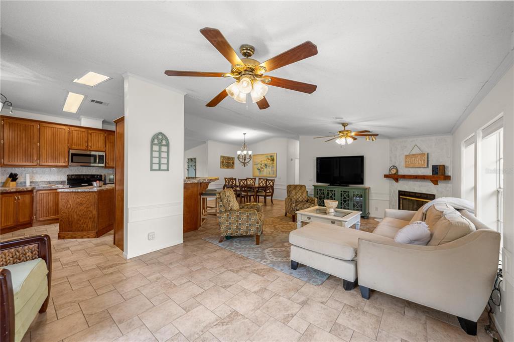 An open-concept living room and kitchen featuring tile flooring, wooden cabinets, and ceiling fans — 18850 SE 12TH LANE, WILLISTON, FL