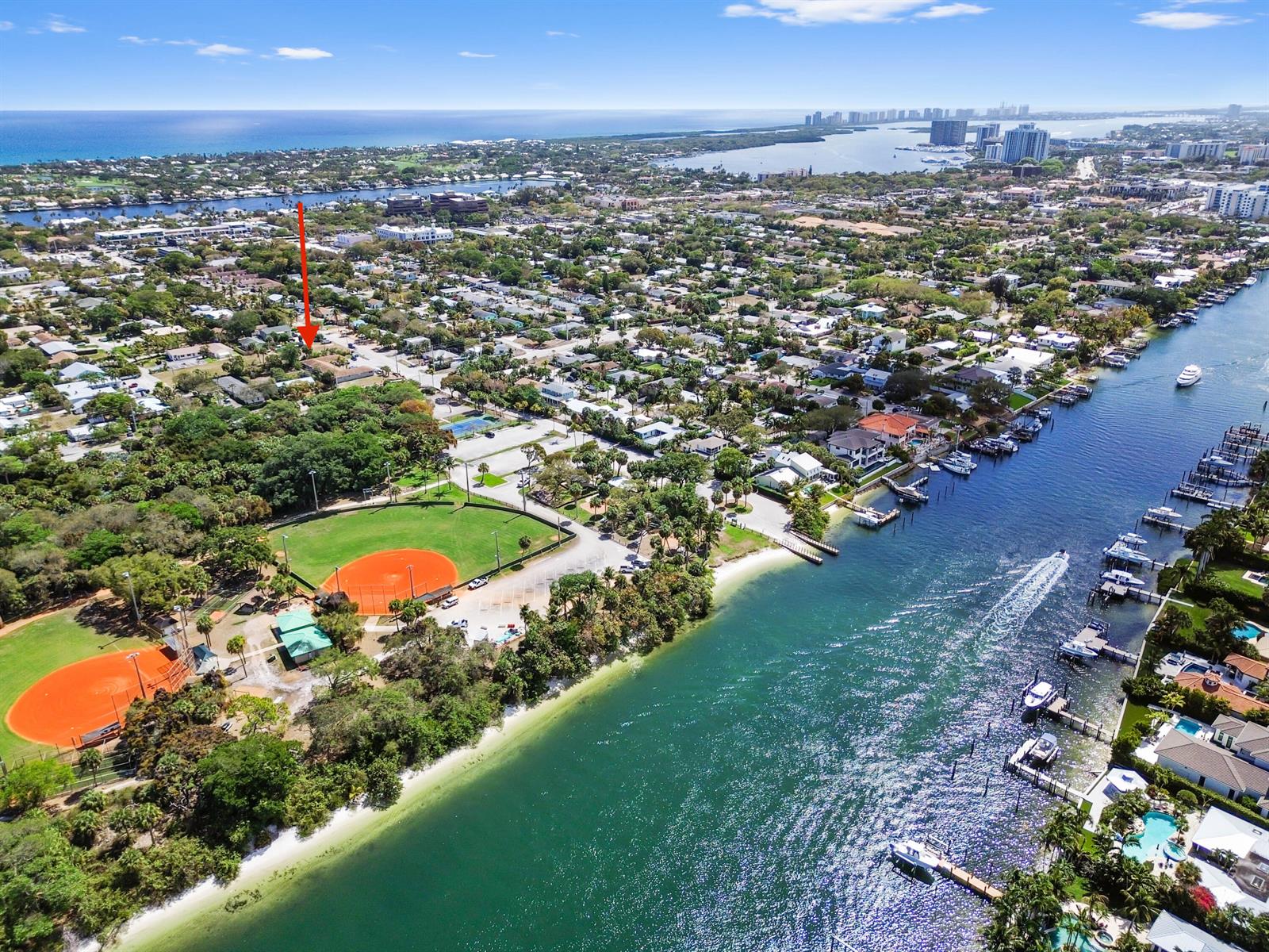 Aerial view of a coastal neighborhood with baseball fields, a canal, and a red arrow — 1955 Juno Road, North Palm Beach FL 33408, NORTH PALM BEACH, FL
