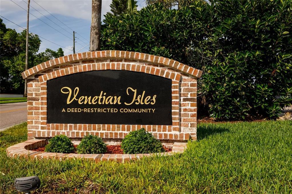 A brick monument sign displays the name Venetian Isles in a landscaped residential area — 1985 MICHIGAN AVENUE NE, ST PETERSBURG, FL