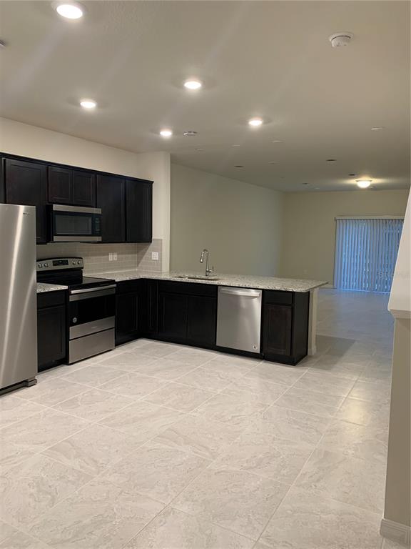 A kitchen features dark wood cabinets, granite countertops, stainless steel appliances, and light tile flooring — 2567 BUENA VIEW ROAD, KISSIMMEE, FL