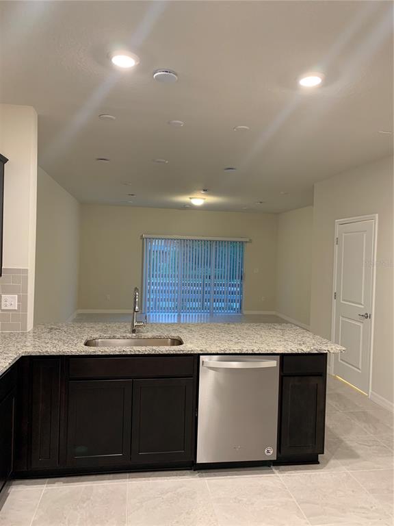 A kitchen island with a stainless steel dishwasher and sink faces a living area — 2567 BUENA VIEW ROAD, KISSIMMEE, FL
