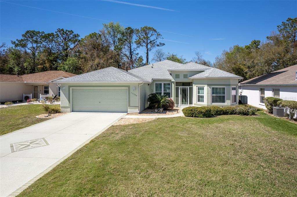 A light green single-story house with a two-car garage and a paved driveway — 15304 SW 15TH TERRACE ROAD, OCALA, FL
