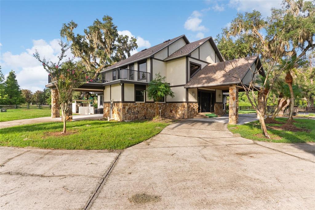 A two-story house with a stone base, a covered entryway, and an upper-level balcony — 12311 KELSO ROAD, THONOTOSASSA, FL
