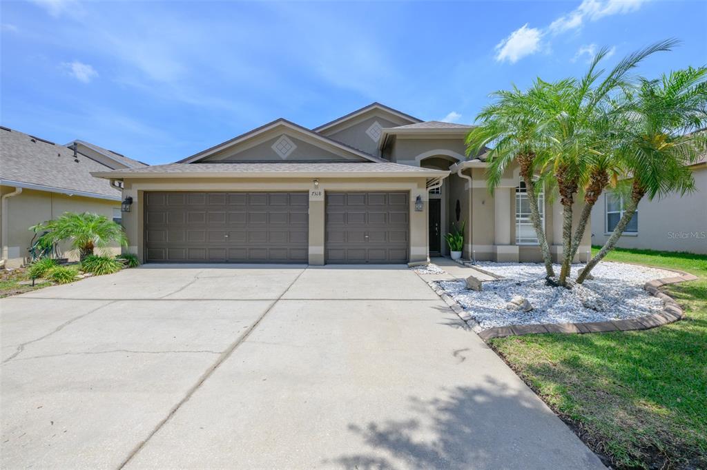 A single-story house with a two-car garage, a concrete driveway, and a palm tree — 7318 GUILFORD PINE LANE, APOLLO BEACH, FL