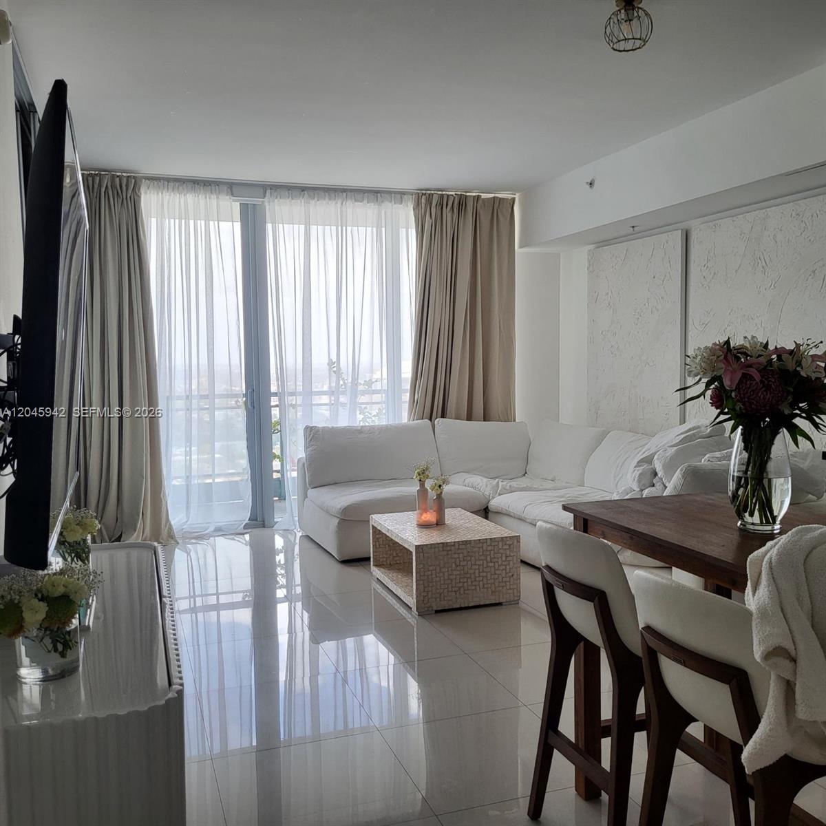A living room features a white sectional sofa, a textured coffee table, and tile flooring — 92 SW 3rd St # 3207, Miami FL 33130, MIAMI, FL