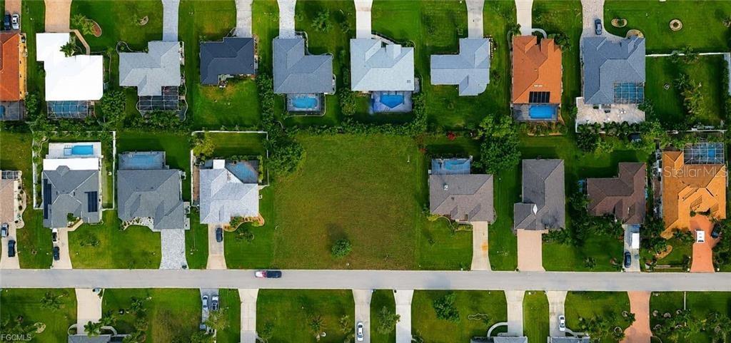 An aerial view shows a vacant residential lot situated between two houses in a neighborhood — 1825 SW 47TH TERRACE, CAPE CORAL, FL