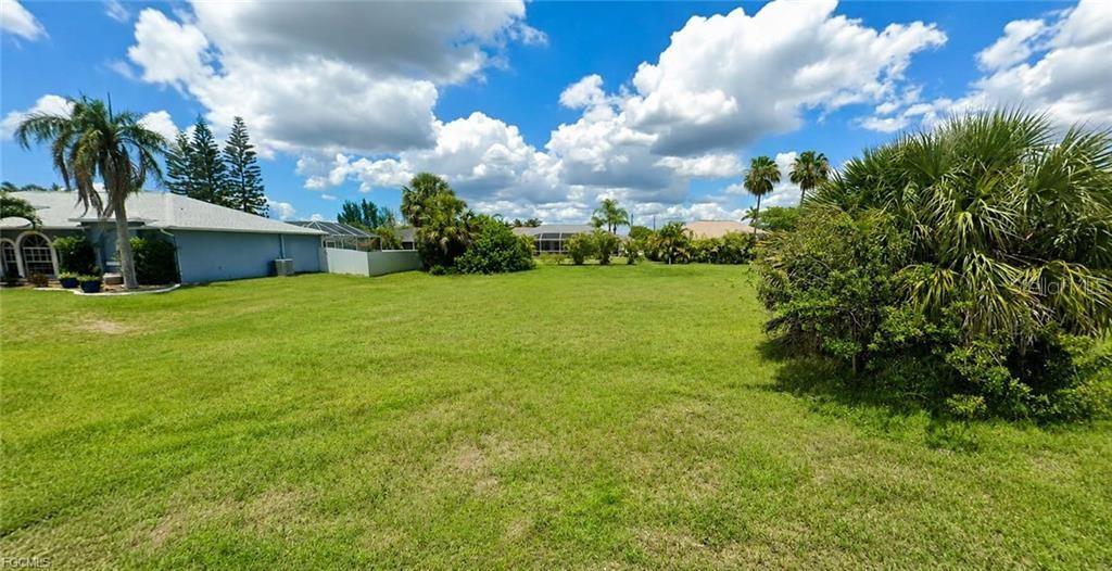 A large, grassy vacant lot is bordered by a house and various palm trees — 1825 SW 47TH TERRACE, CAPE CORAL, FL