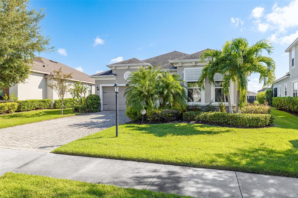 A single-story house with a paved driveway, palm trees, and a green lawn — 5213 HORIZON COVE, BRADENTON, FL