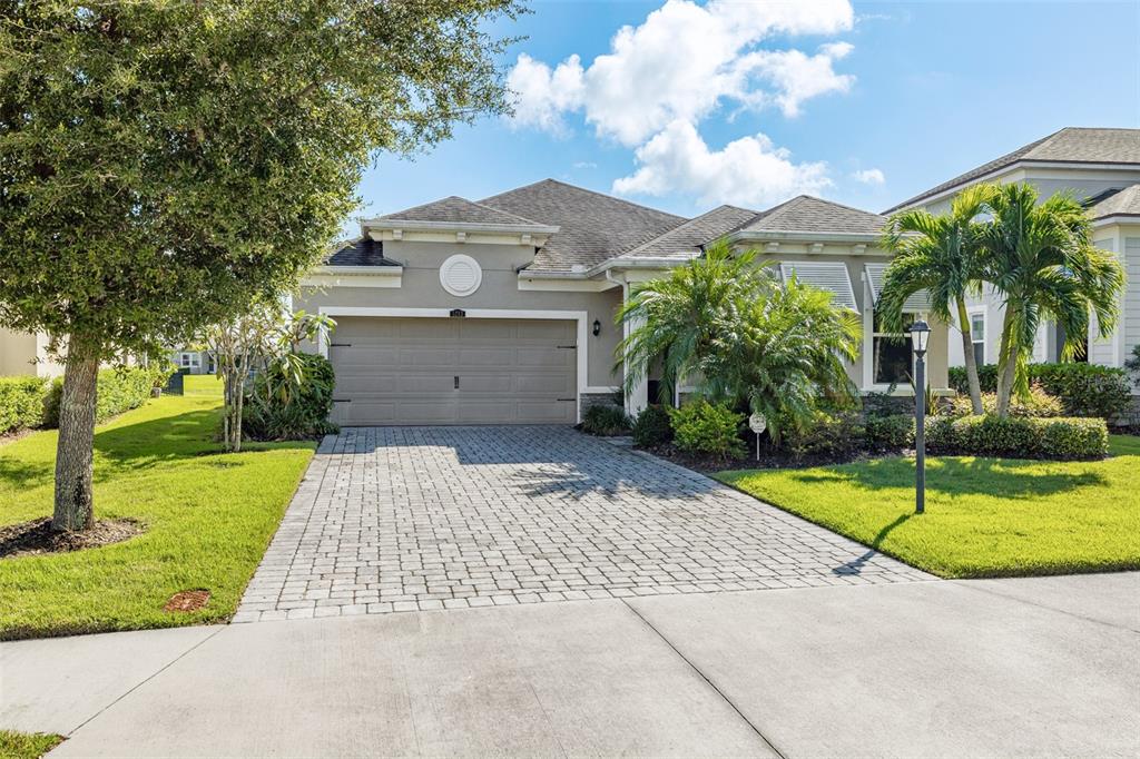 A single-story house with a paved driveway, a two-car garage, and palm trees in front — 5213 HORIZON COVE, BRADENTON, FL