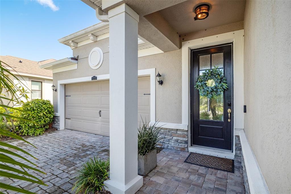 A front exterior view showing a paved driveway, a garage, and a black front door — 5213 HORIZON COVE, BRADENTON, FL