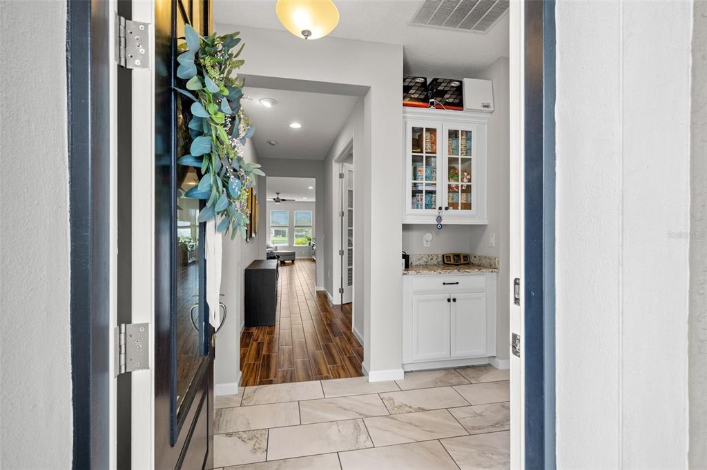 A view through an open doorway into a foyer with tile flooring and built-in cabinetry — 5213 HORIZON COVE, BRADENTON, FL