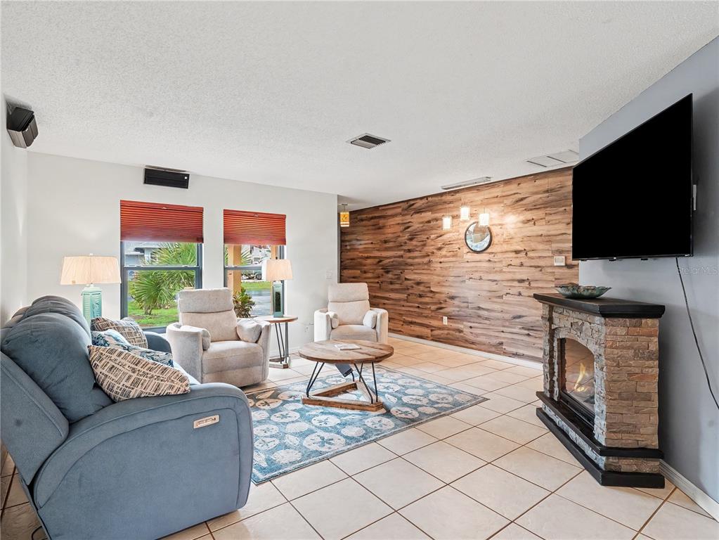 A living room features a stone fireplace, wood-paneled accent wall, and blue sofa — 2320 LAKE SHORE DRIVE, NOKOMIS, FL