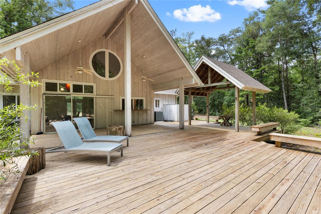 A large wooden deck features two lounge chairs in front of a rustic house exterior — 8250 WAUKEENAH HIGHWAY, MONTICELLO, FL