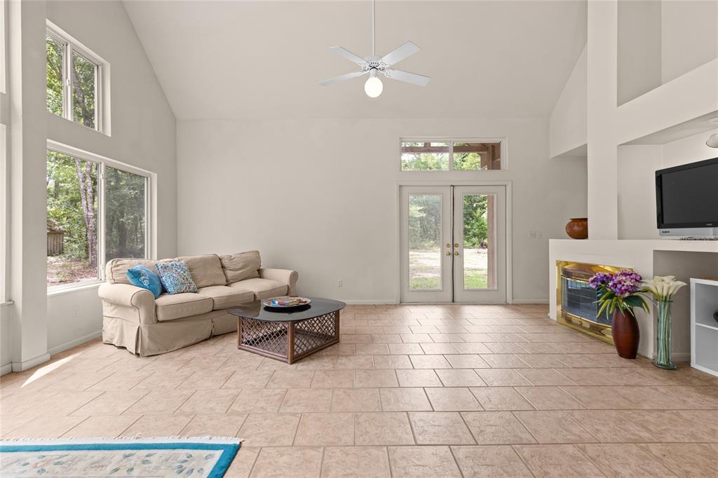 A living room with vaulted ceilings, tile flooring, a fireplace, and a beige sofa — 8250 WAUKEENAH HIGHWAY, MONTICELLO, FL