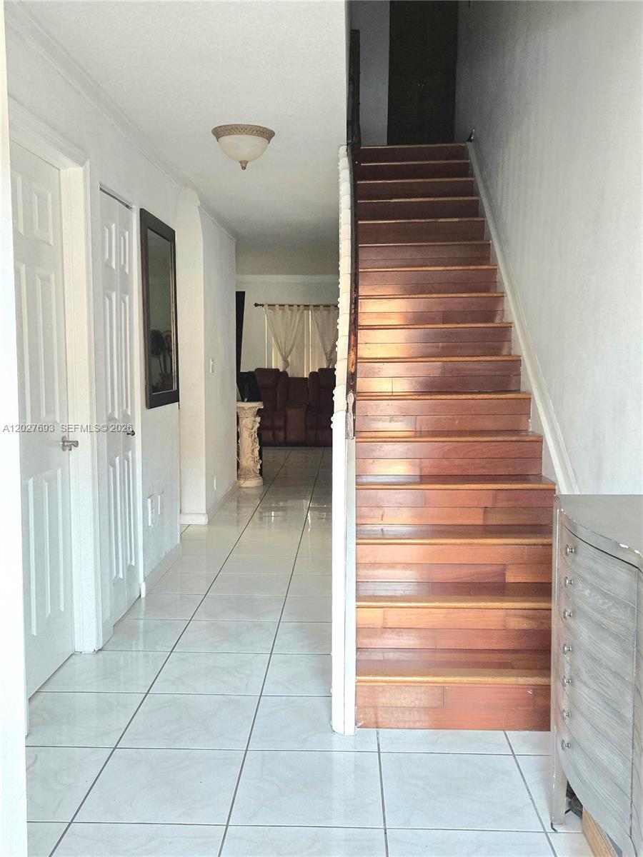 A tiled hallway leads to a living area beside a wooden staircase — 7255 NW 173rd Dr # 8, Hialeah FL 33015, HIALEAH, FL