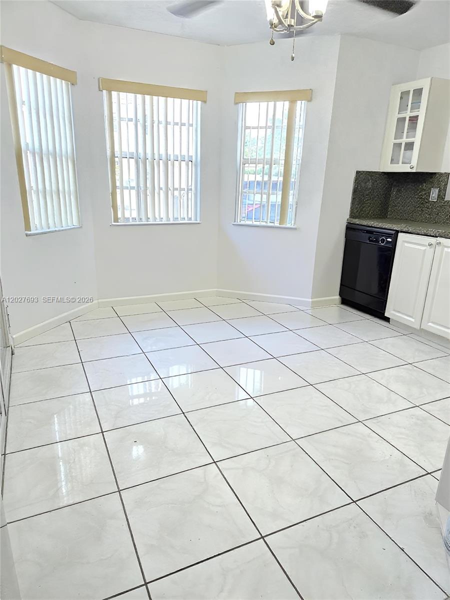 A kitchen area features white tile flooring, white cabinets, a black dishwasher, and three windows — 7255 NW 173rd Dr # 8, Hialeah FL 33015, HIALEAH, FL